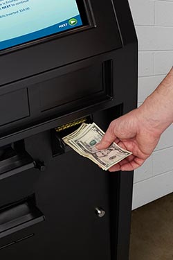 Hand putting cash into booking kiosk