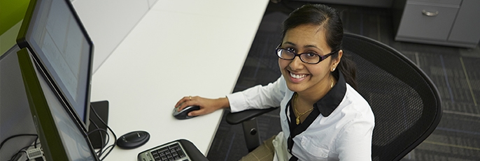 Smiling female customer service representative looking up from desk